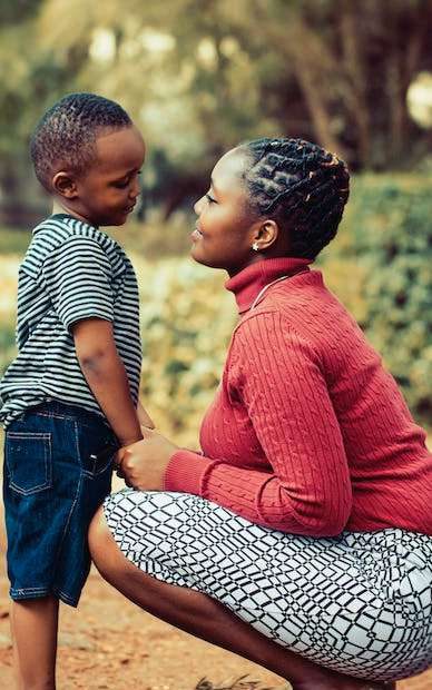 A mother kneeling to talk with her young son outdoors